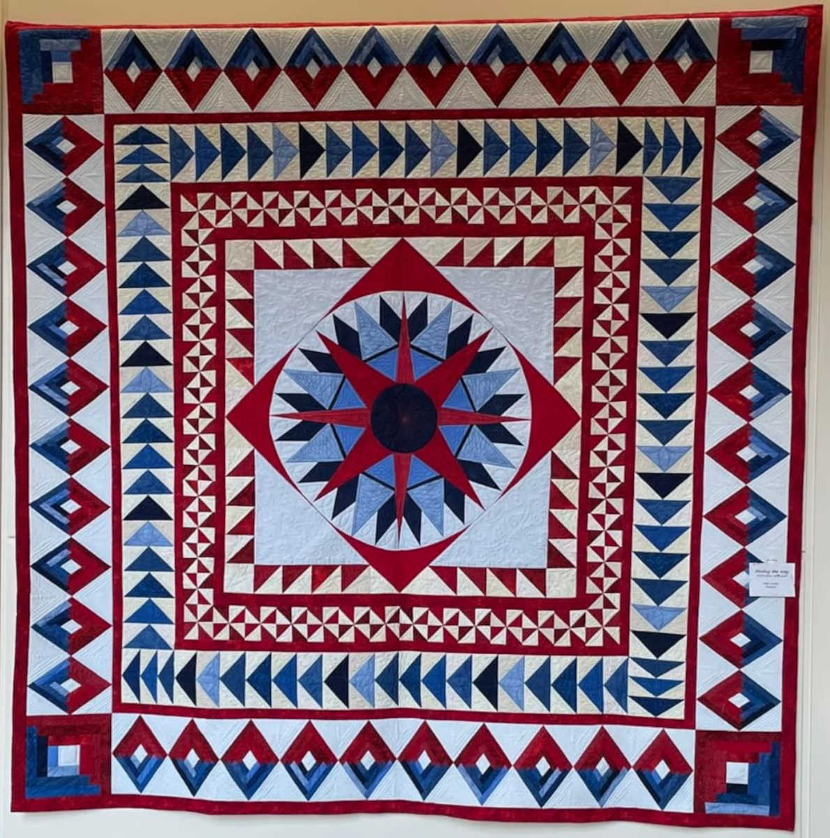 The 2020 - 2021 raffle quilt was designed by Adrienne Randal, with Judy Shapiro designing the center medallion. It was pieced by Adrienne Randal and Jeanette Bayliss and custom quilted by Debbie Werker.